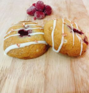 Cookie vàng mềm với nhân mứt framboise hình trái tim ở giữa và socola trắng xung quanh, đặt trên nền pastel hồng