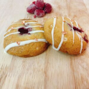 Cookie vàng mềm với nhân mứt framboise hình trái tim ở giữa và socola trắng xung quanh, đặt trên nền pastel hồng