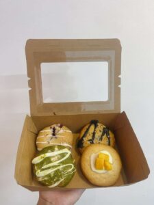 Hộp kraft vuông với 4 chiếc cookie: matcha, framboise, dừa, xoài, logo Mimi Bakes, nền pastel