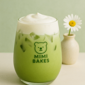 Ly matcha latte với lớp kem mịn bên trên, đá viên, logo Mimi Bakes, nền xanh pastel