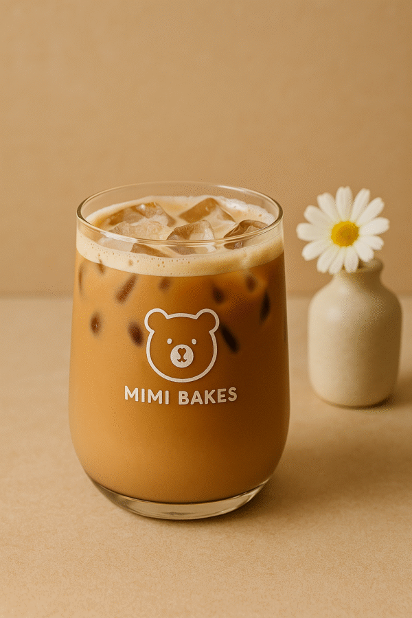 Ly cà phê sữa với đá viên, logo Mimi Bakes, nền màu nâu kem dịu nhẹ