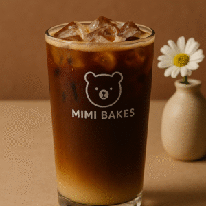 Ly cà phê sữa đá với hai tầng màu nâu đậm và sữa đặc, đá viên, logo Mimi Bakes, nền nâu pastel
