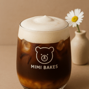 Ly cà phê phin với kem sữa muối và đá viên trong ly, logo Mimi Bakes, nền nâu pastel