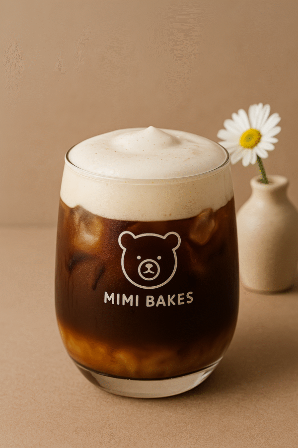 Ly cà phê phin với kem sữa muối và đá viên trong ly, logo Mimi Bakes, nền nâu pastel